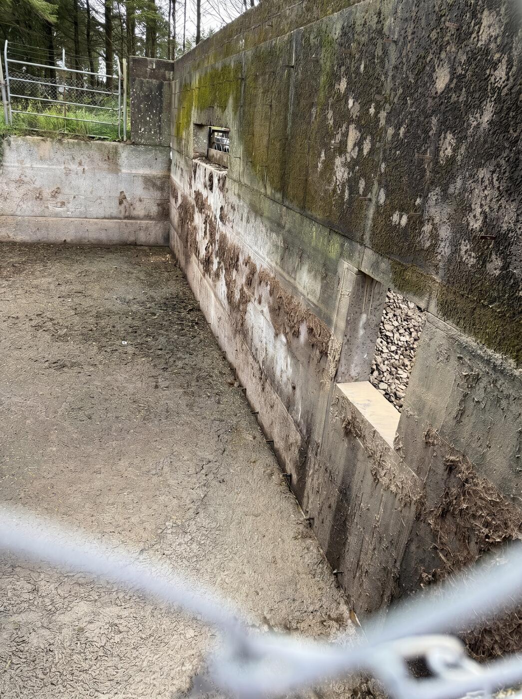 An external concrete retaining wall with a rectangular section cut and removed