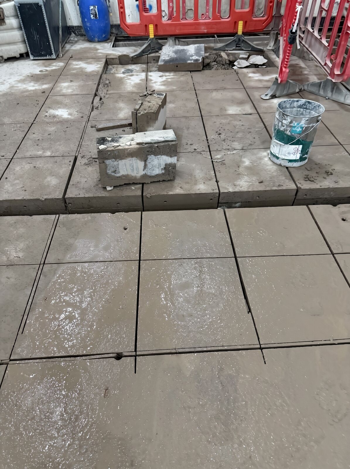Saw cut concrete slabs with clean straight cut lines and a removed section beside a site barrier