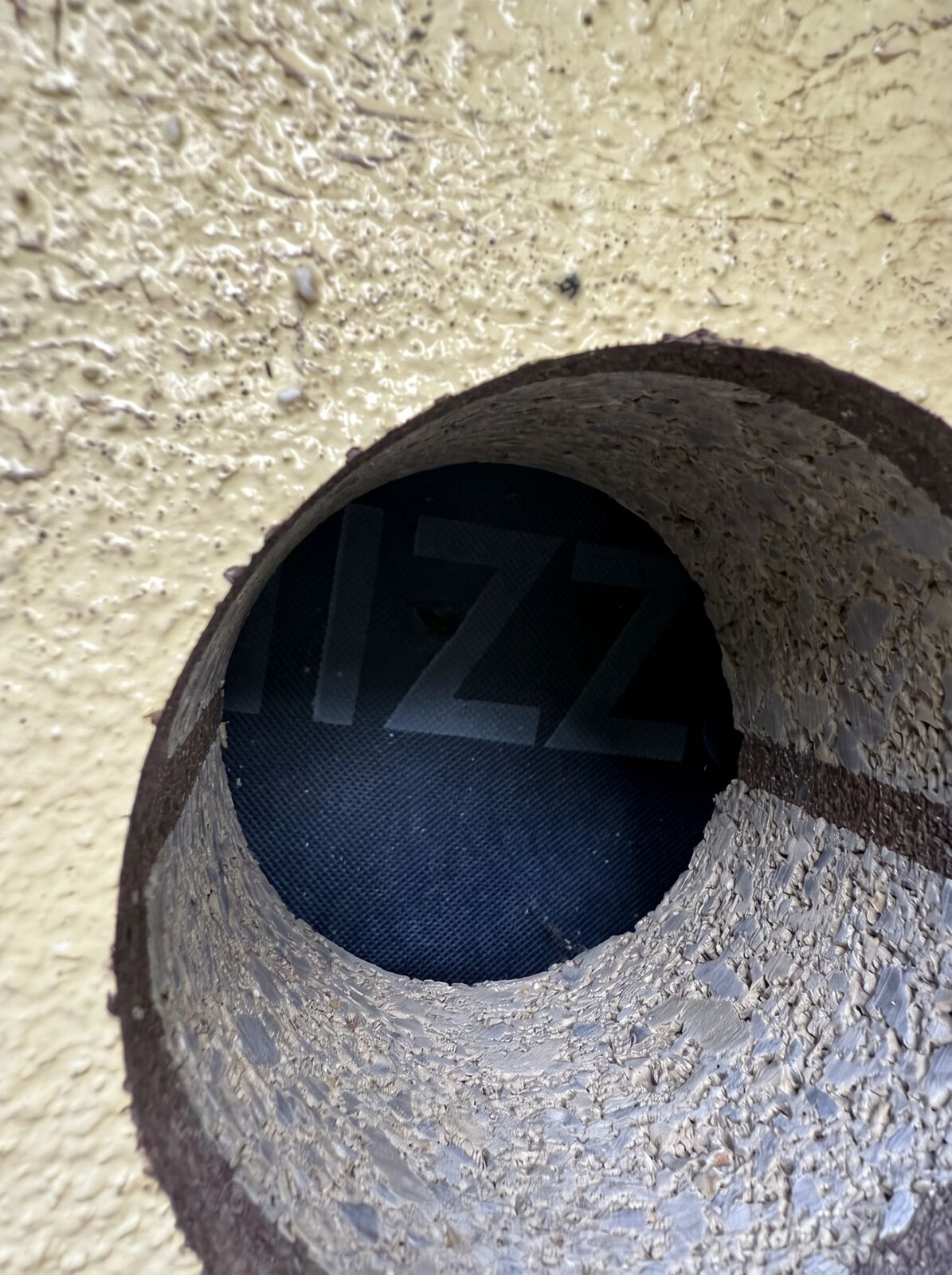 A clean cored vent hole through a rendered external wall with the vent mesh visible behind